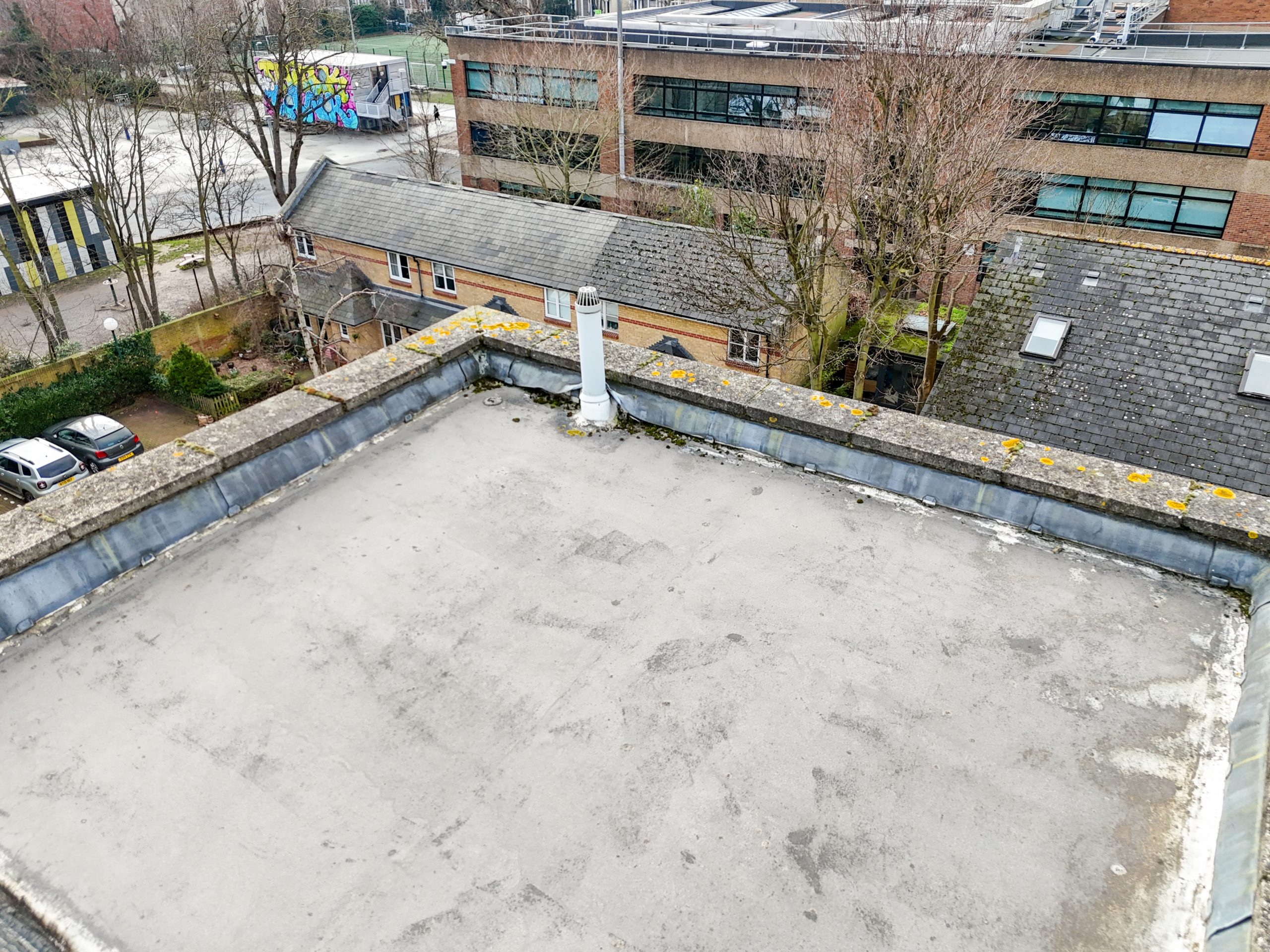 Apartment building roof detail showing parapet coping stones and drainage components