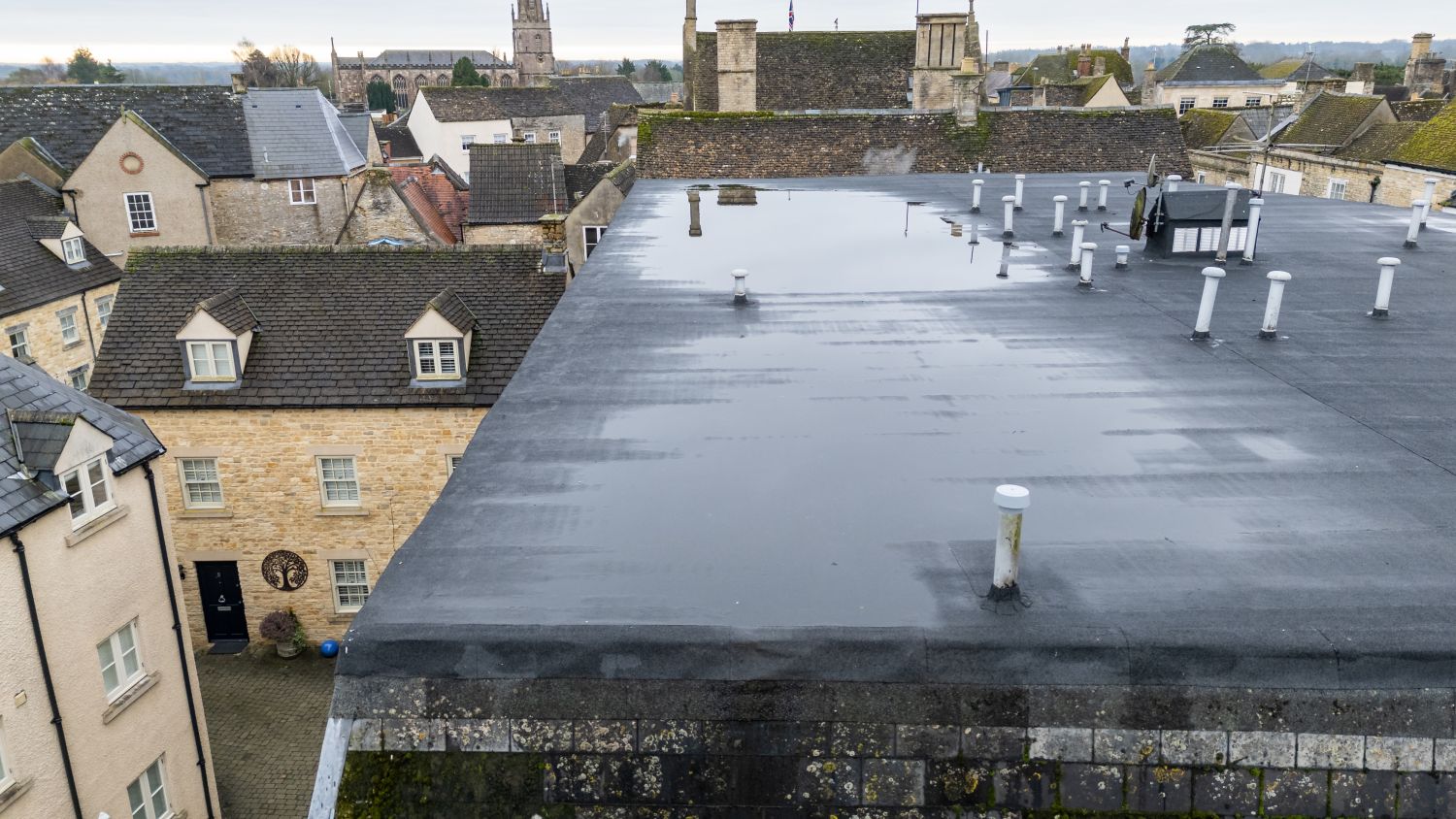 Drone roof survey image showing water pooling on a flat roof of a small block of flats in Tetbury